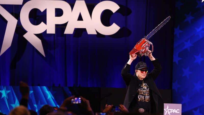 Elon Musk com uma motosserra no CPAC em 2025