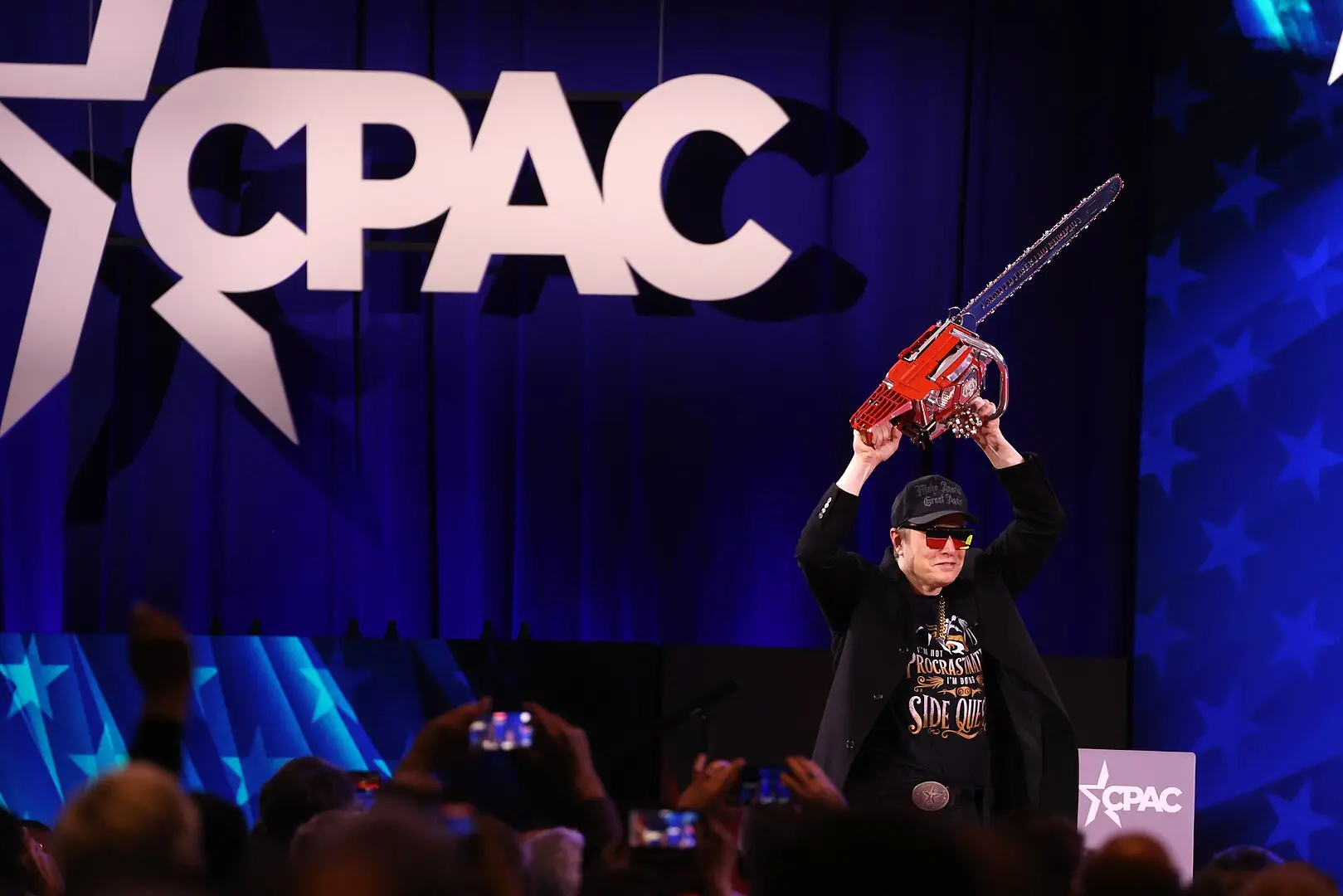 Elon Musk com uma motosserra no CPAC em 2025