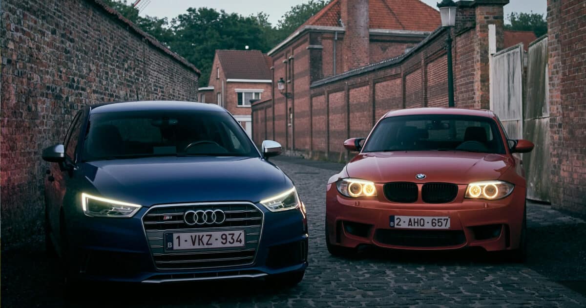 Dois carros, um Audi S1, e um BMW 1M, parados lado a lado