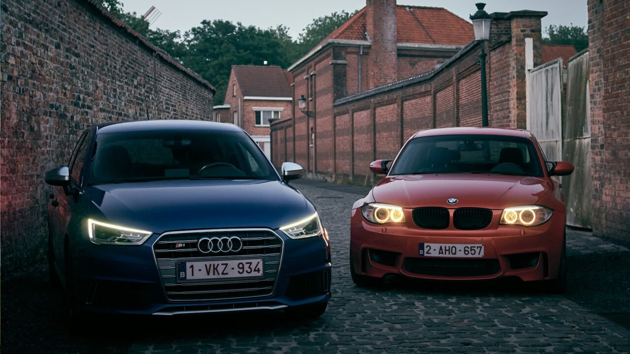 Dois carros, um Audi S1, e um BMW 1M, parados lado a lado