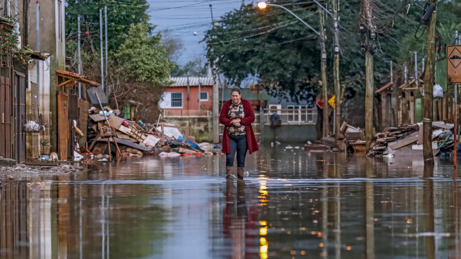 Vítima da enchente do Rio Grande do Sul em 2024 anda por rua alagada 
