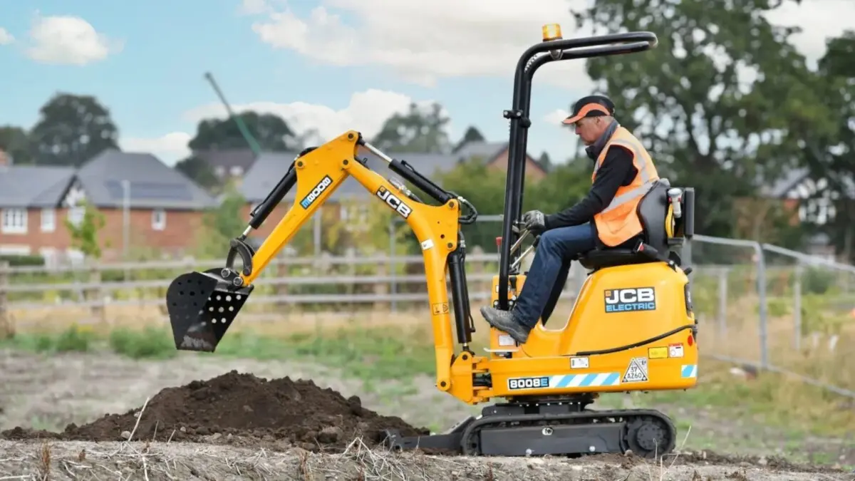 Empresário britânico Colin Ash dirigindo escavadeira elétrica num campo na Inglaterra
