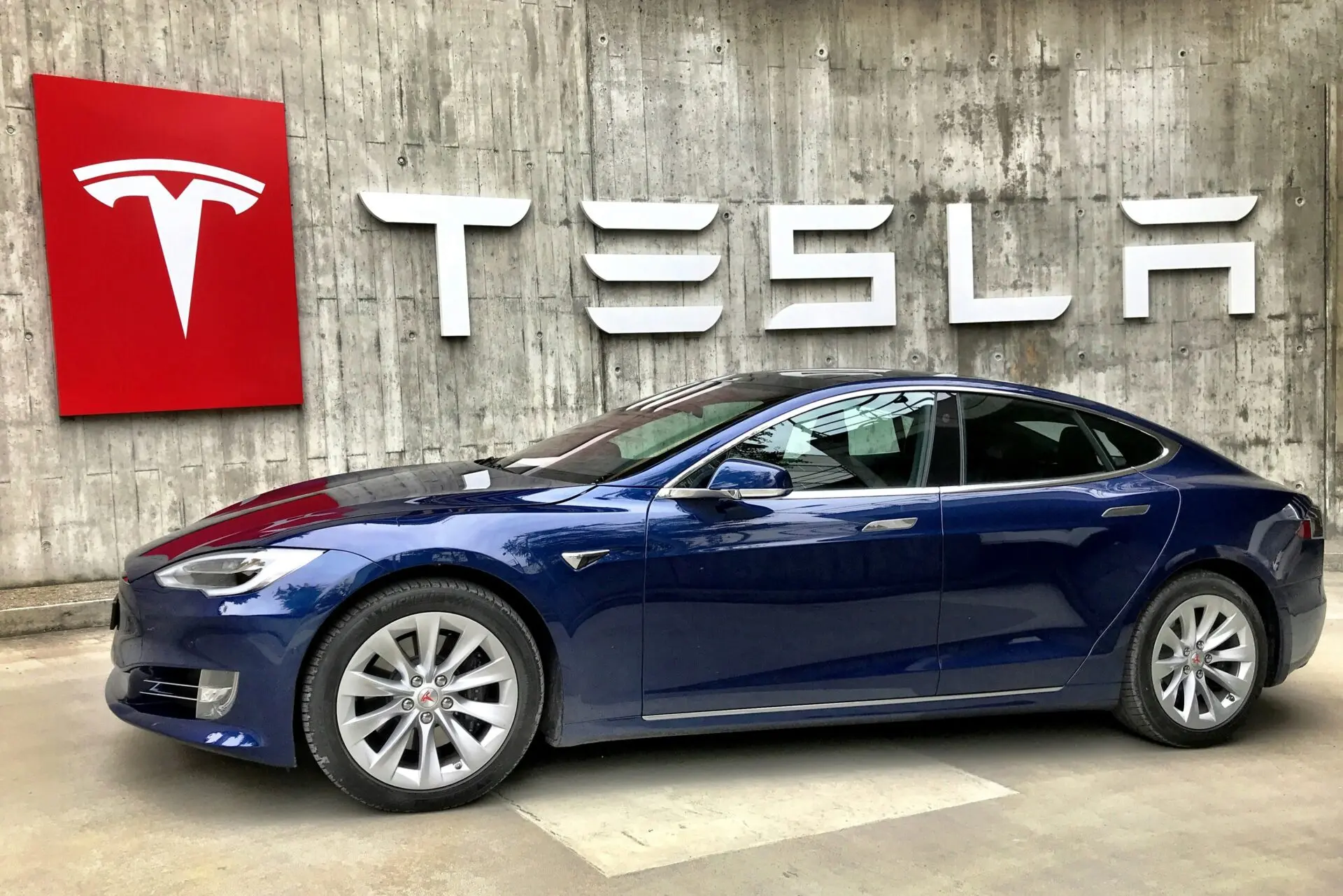 Tesla Model Y diante de um muro com a marca Tesla