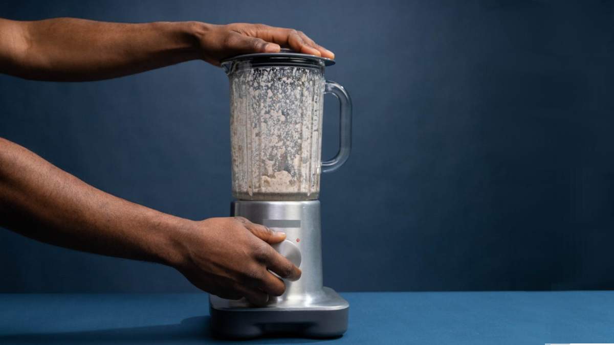 Foto de uma pessoa prestes a ligar um liquidificador