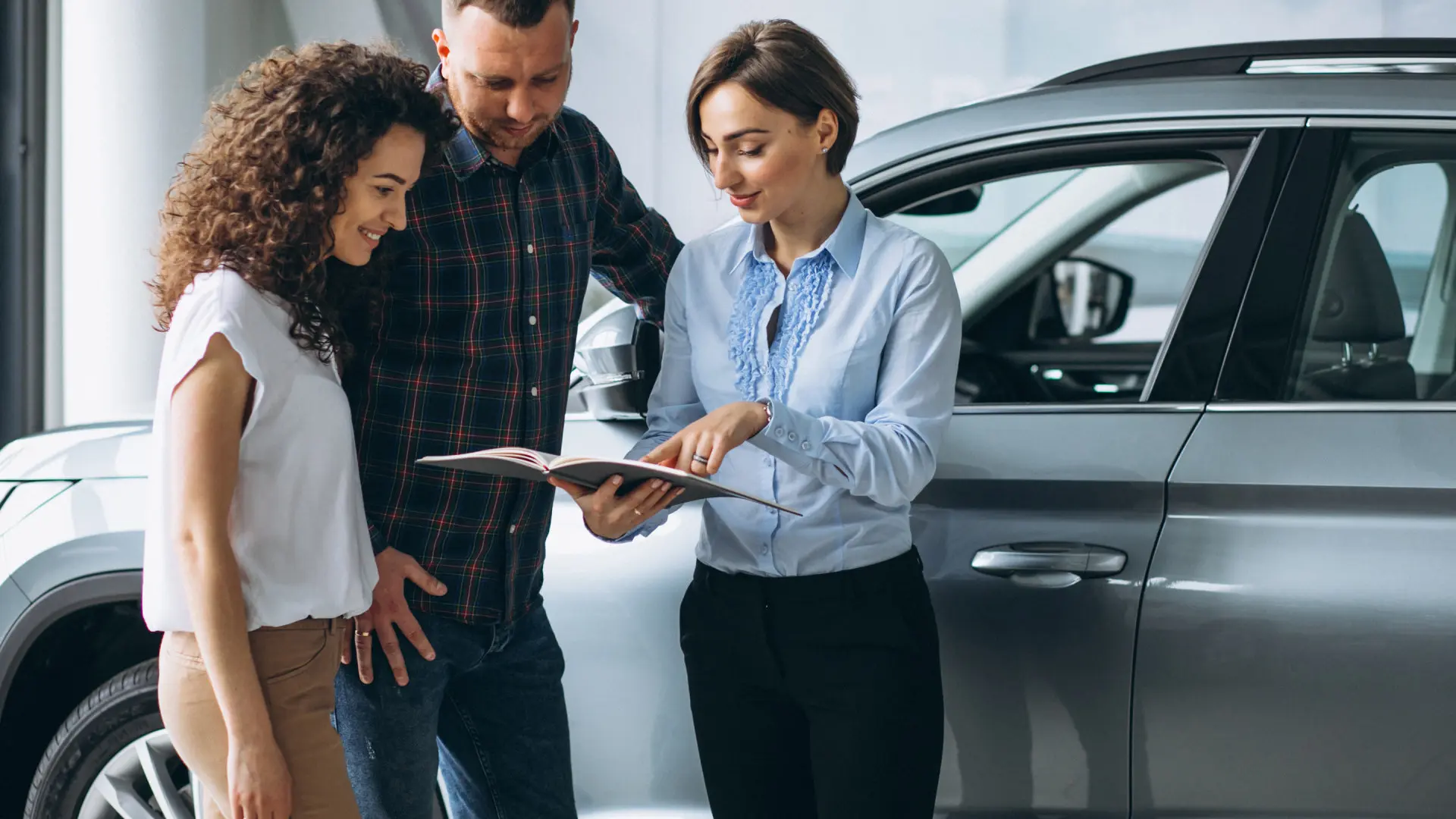 Imagem ilustrtiva de uma mulher e um homem comprando um carro de uma vendedora na concession[aria