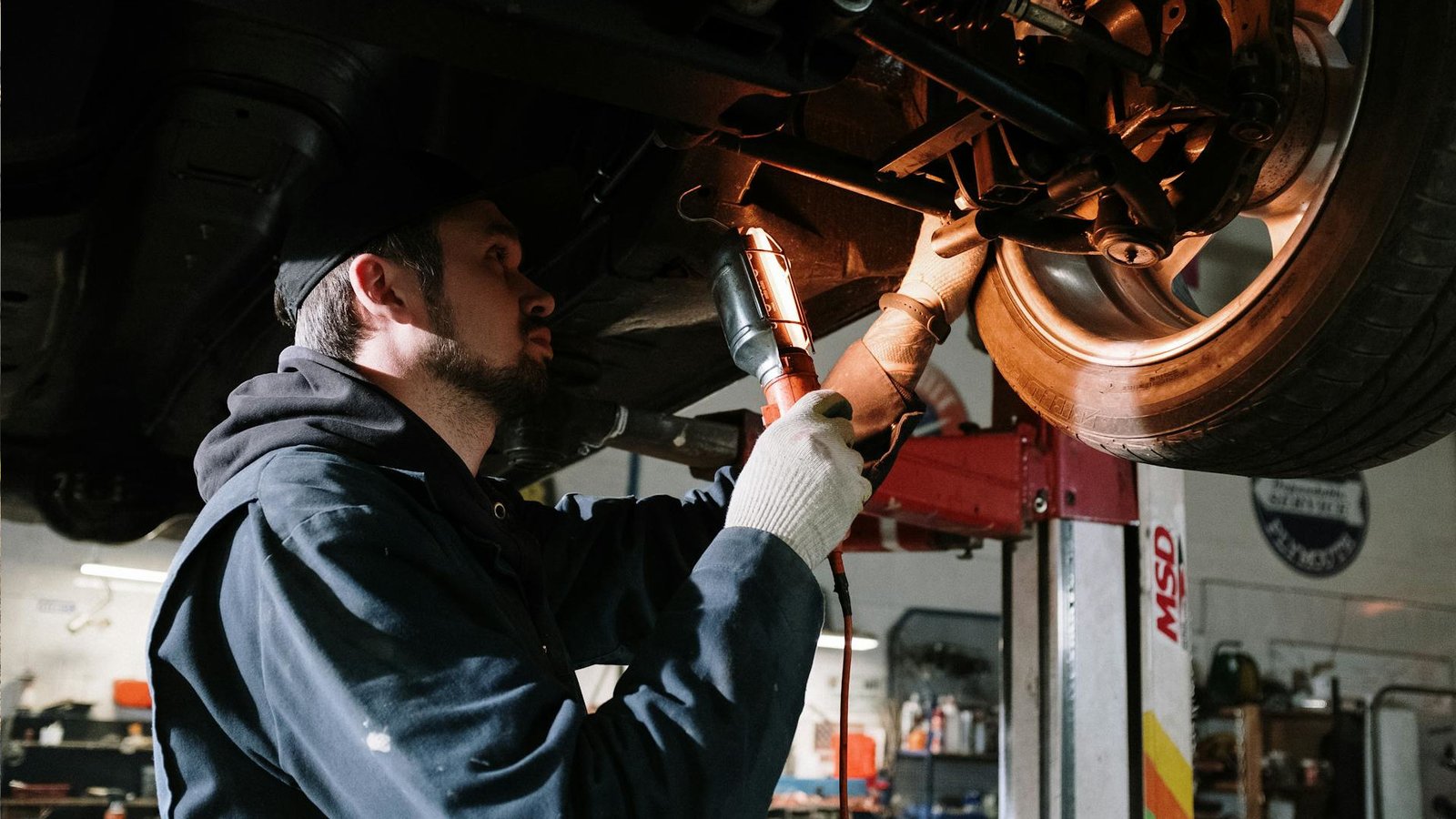 Mecânico usando uma lanterna para ver a parte de baixo de um carro elétrico