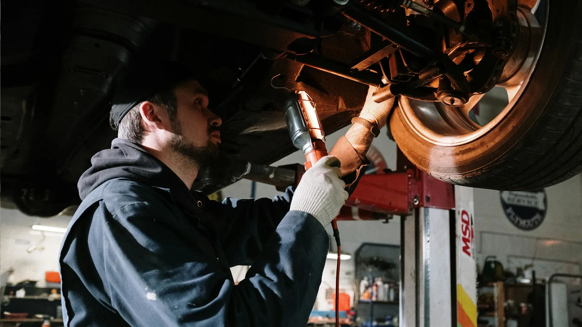 Mecânico usando uma lanterna para ver a parte de baixo de um carro elétrico