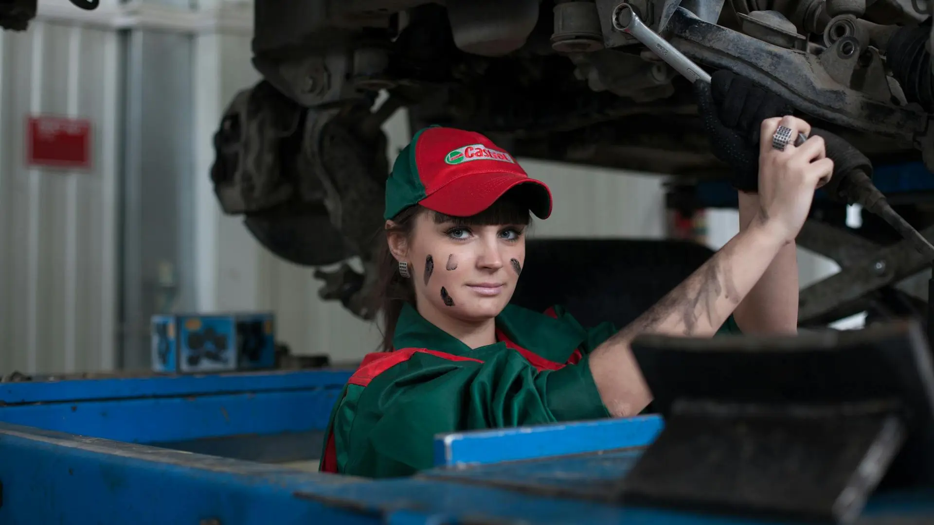 Foto de mulher mecânica dando manutenção em carro, sob o elevador