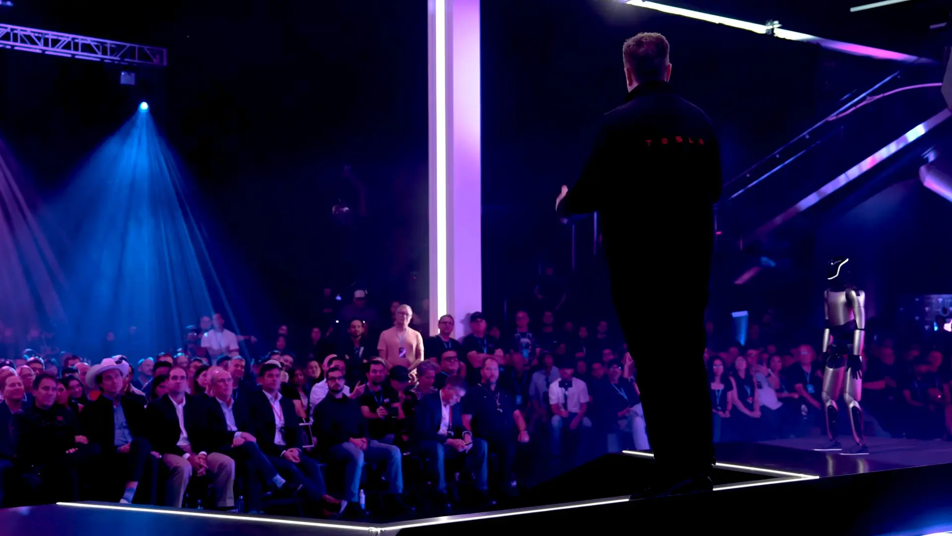 Elon Musk falando à platéia na conferência de investidores da Tesla em 6 de outubro de 2025, visto de costas