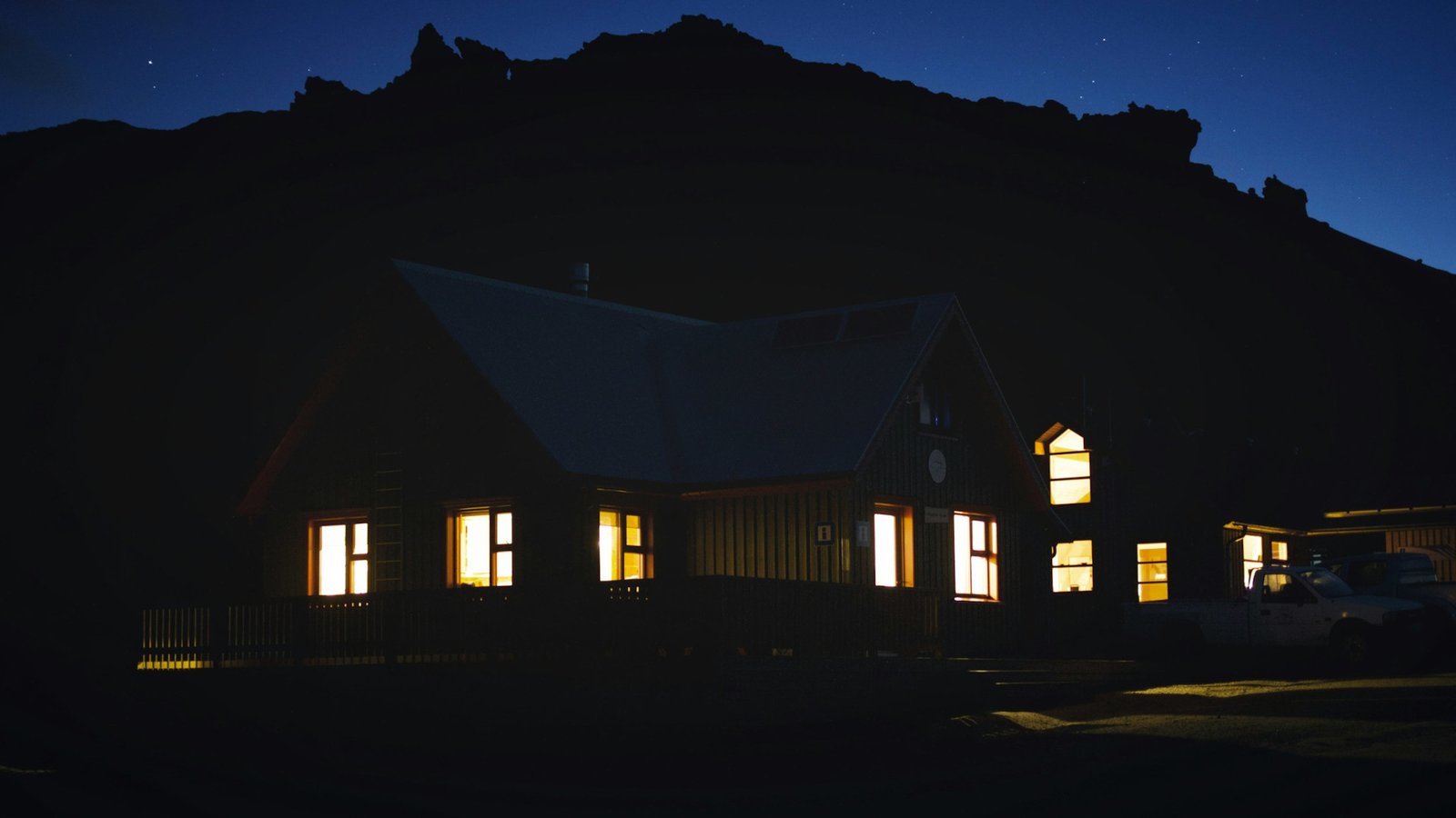 Casa fotografada à noite, com carro na garagem