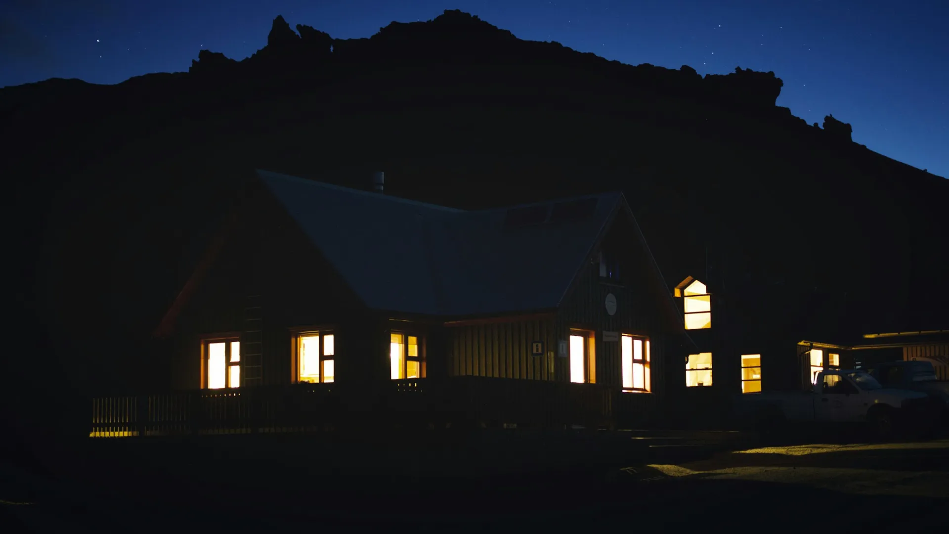 Casa fotografada à noite, com carro na garagem
