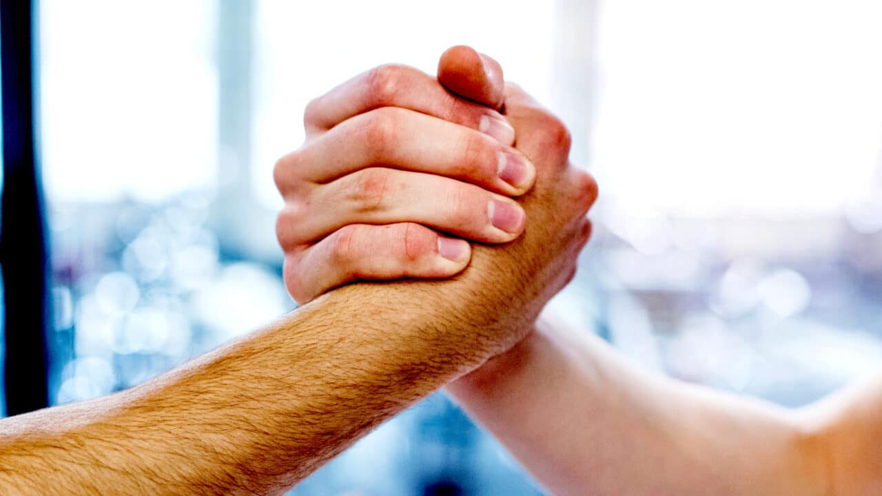 Um aperto de mão com as mãos para cima, como numa queda de braço