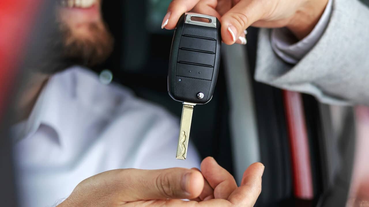 Homem recebendo chaves de carro de vendedora