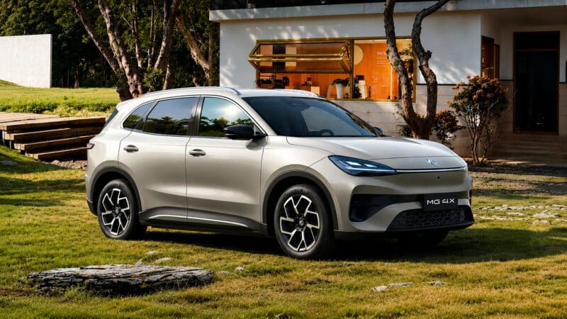 SUV elétrico MG 4X prata estacionado em área gramada, cercado por árvores