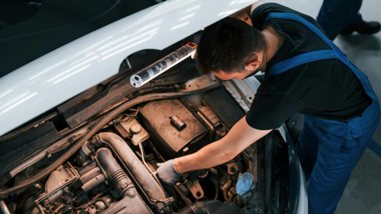 Mecânico consertando o motor de um carro, com o capô aberto