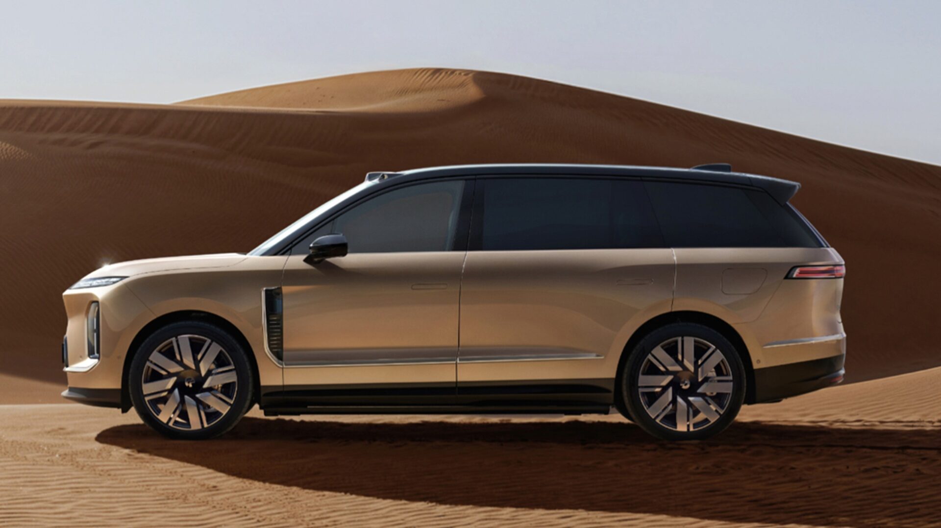 Lateral do UV elétrico de luxo NIO ES9 em tom bege claro atravessando dunas no deserto