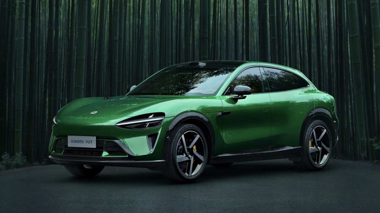 Carro elétrico Xiaomi YU7 na cor verde metálica, estacionado em uma estrada cercada por uma floresta de bambus. O SUV tem design futurista, linhas aerodinâmicas, rodas esportivas e faróis estreitos em LED