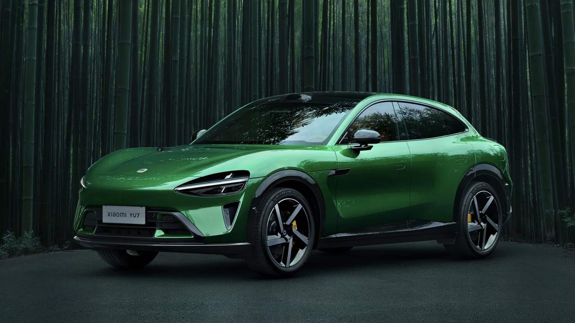 Carro elétrico Xiaomi YU7 na cor verde metálica, estacionado em uma estrada cercada por uma floresta de bambus. O SUV tem design futurista, linhas aerodinâmicas, rodas esportivas e faróis estreitos em LED