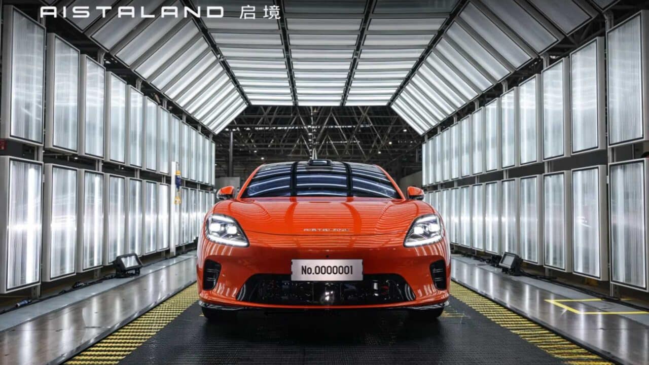 Aistaland GT7 laranja, primeira unidade de produção (No.0000001), visto de frente em cabine de inspeção com painéis de luz na fábrica