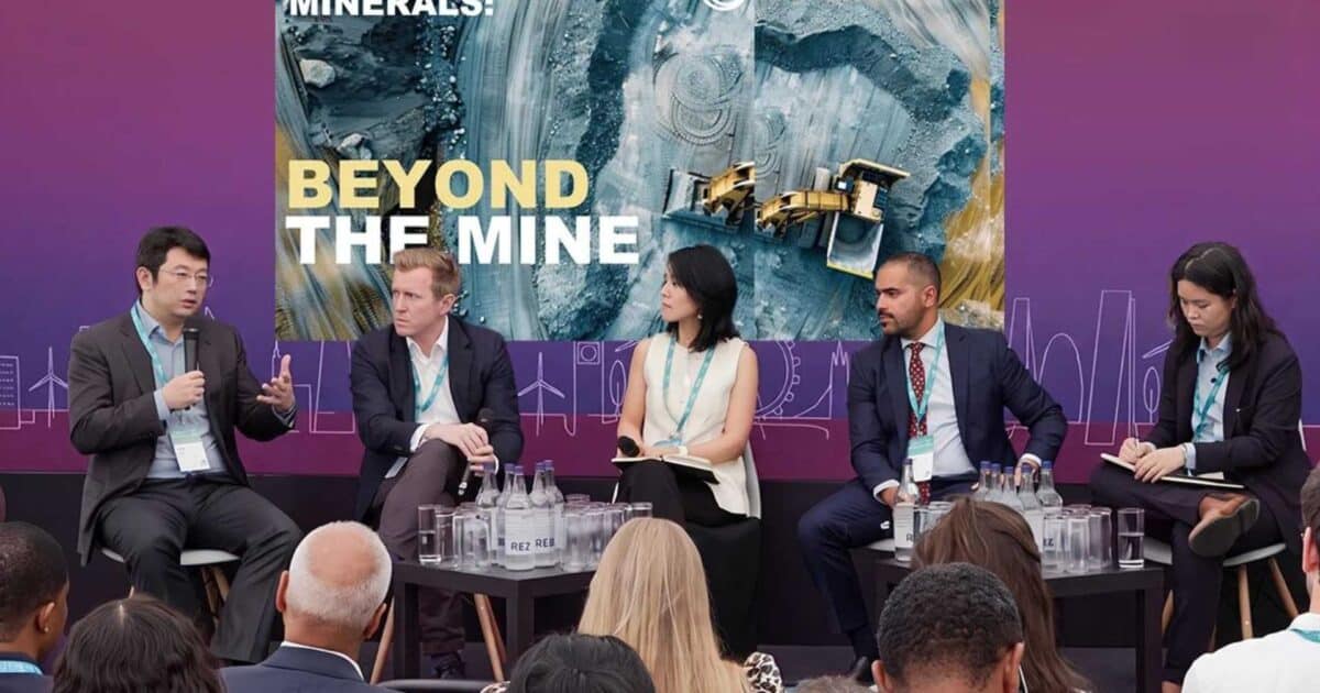 Fotografia de um painel de discussão com cinco palestrantes formais sentados em um palco