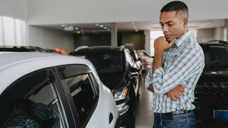 Homem em dúvida olhando para carro usado