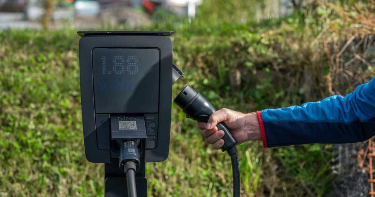 Pessoa conecta cabo em carregador de veículo elétrico