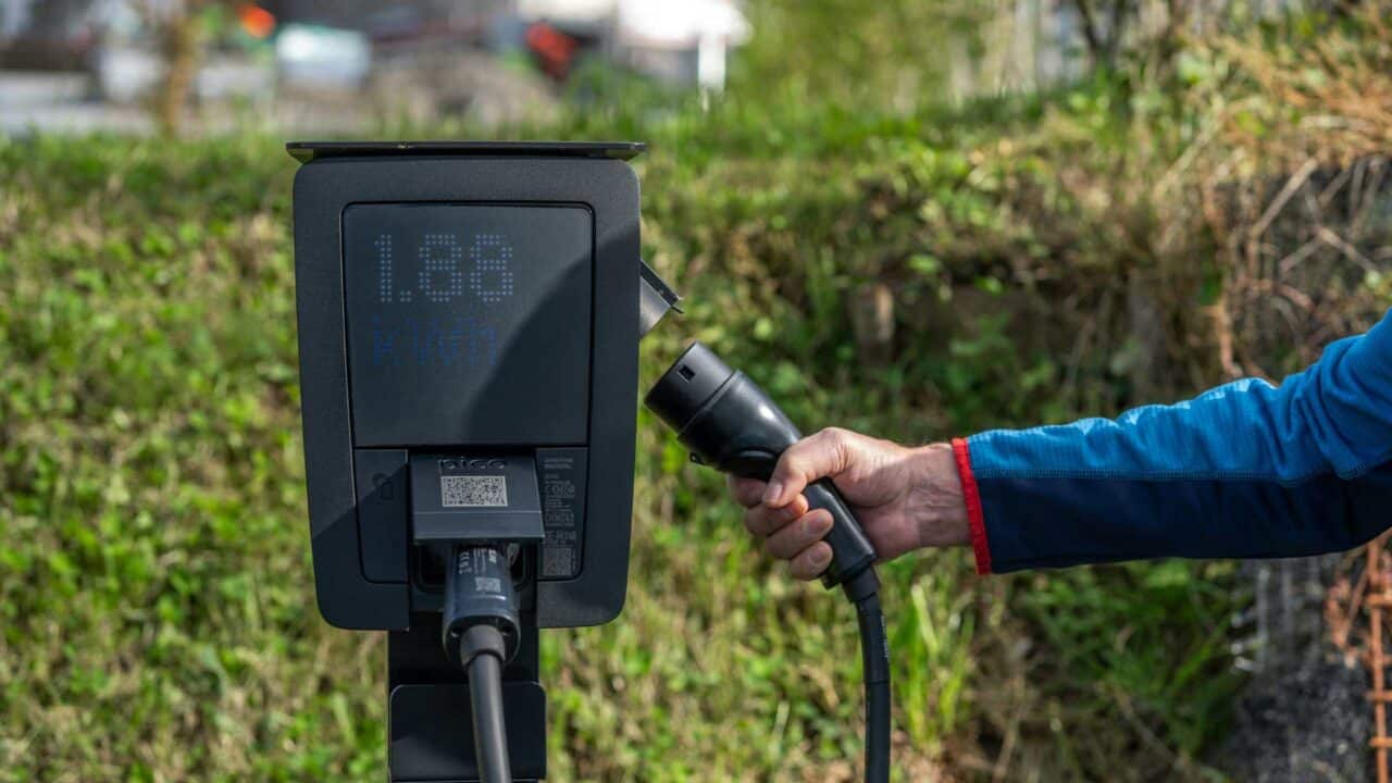 Pessoa conecta cabo em carregador de veículo elétrico