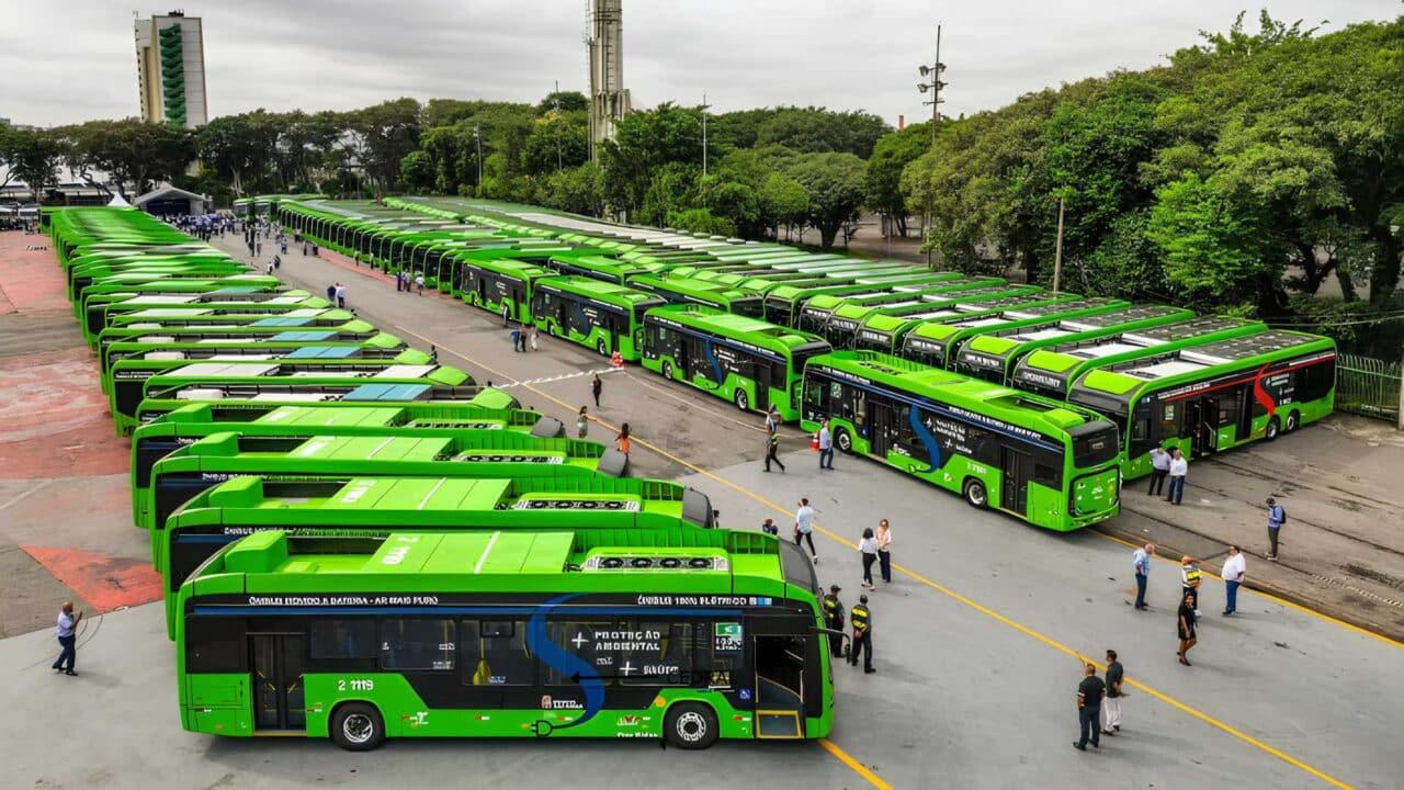 Grande frota de ônibus elétricos urbanos na cor verde enfileirados em um pátio aberto durante evento de entrega oficial
