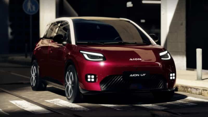 Carro elétrico GAC Aion UT na cor vermelha, com teto branco e iluminação em LED, estacionado em uma rua urbana durante a noite