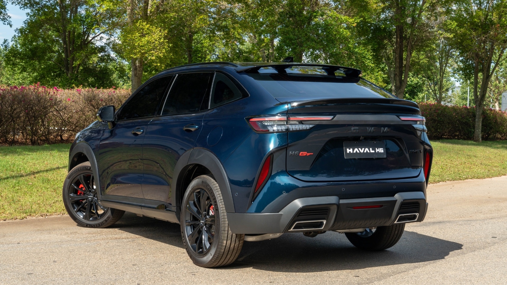 Vista traseira em ângulo três quartos do GWM Haval H6 GT 2027 na cor azul escuro, com lanternas LED em faixa horizontal e spoiler no teto