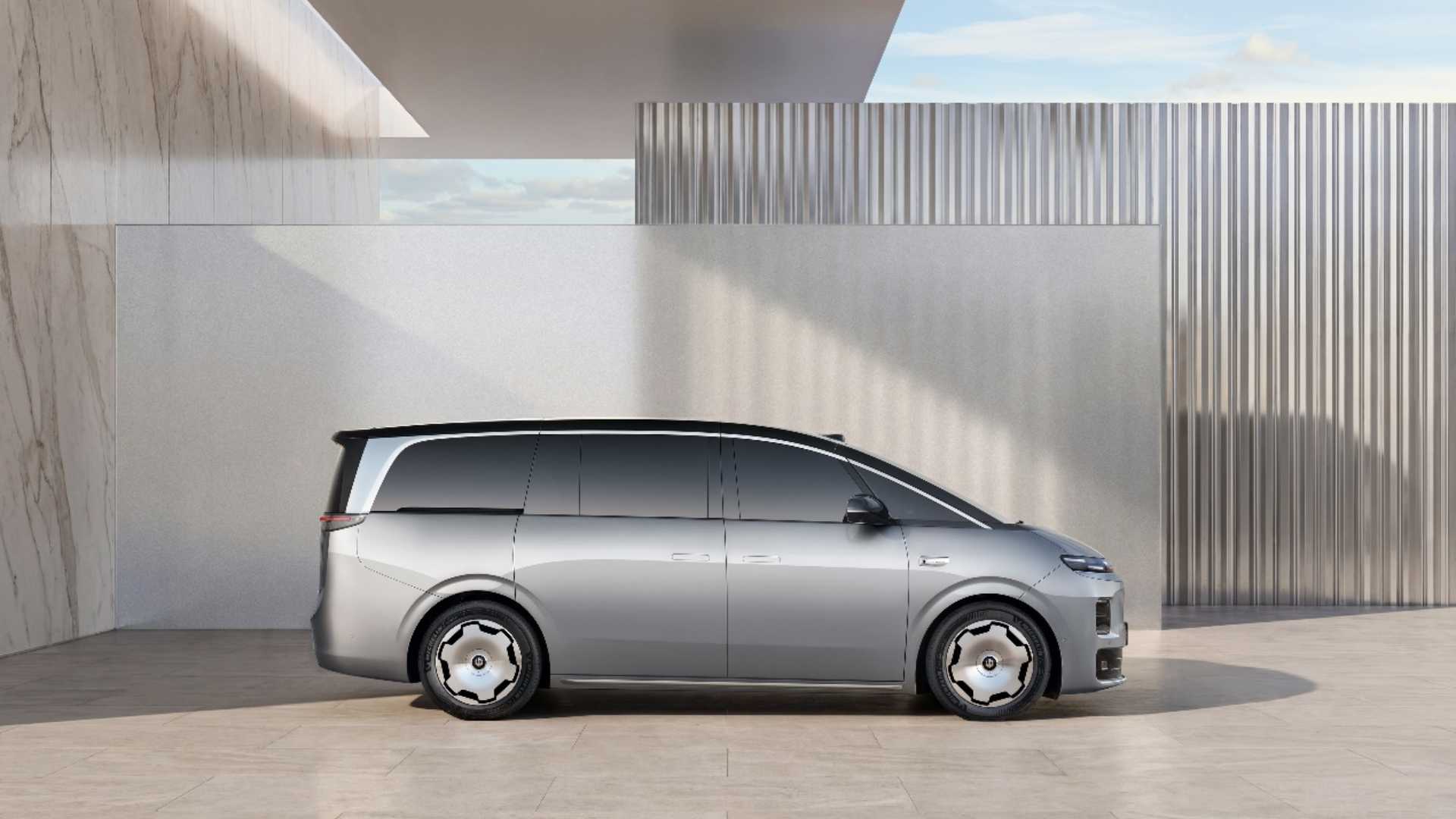 Visão lateral de uma minivan prata e teto preto Leapmotor D99 estacionada diante de uma parede cinza moderna