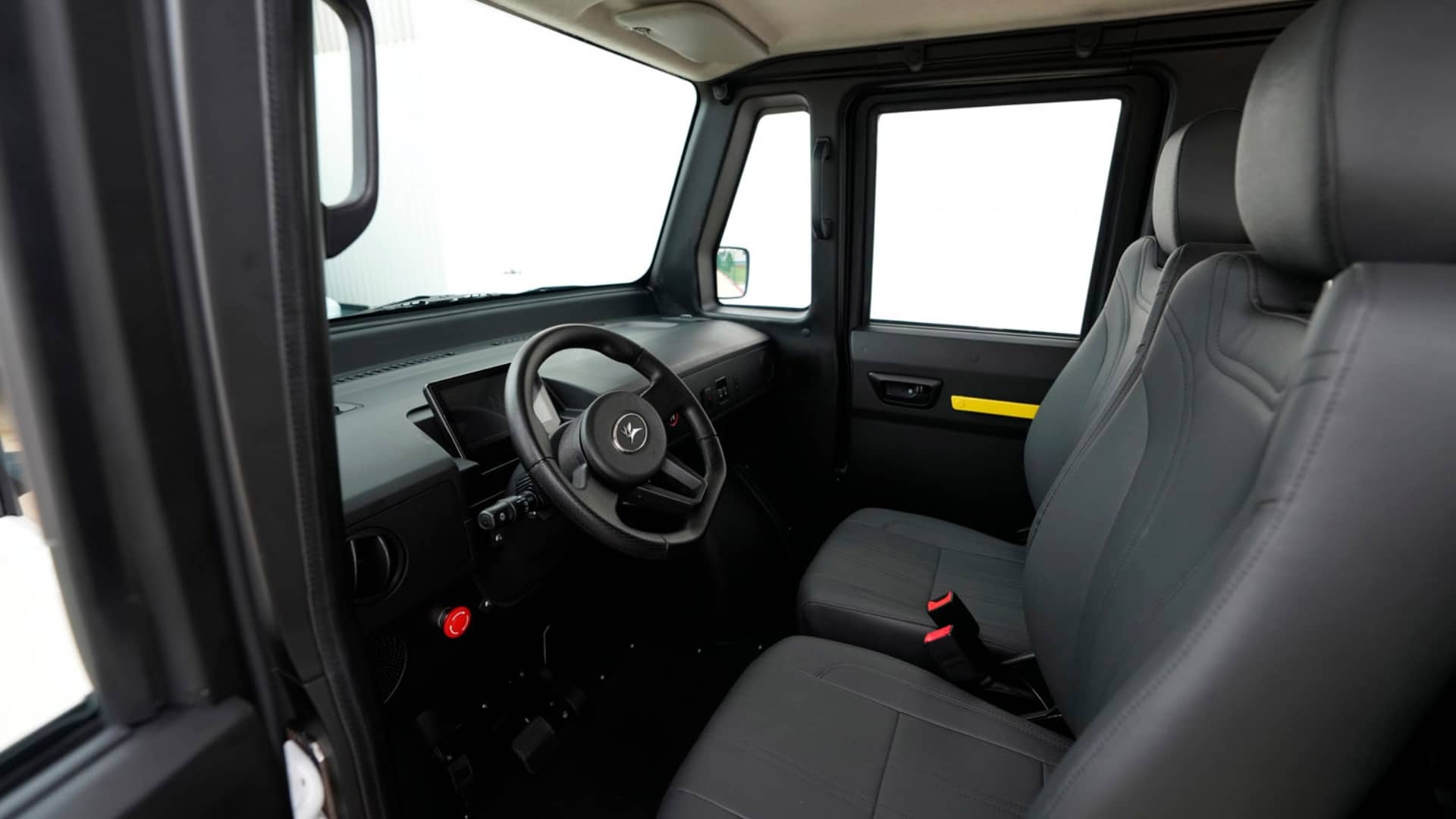 Interior do Olinia 1 com acabamento simples, painel minimalista, volante multifuncional, tela digital e dois bancos dianteiros revestidos em material escuro