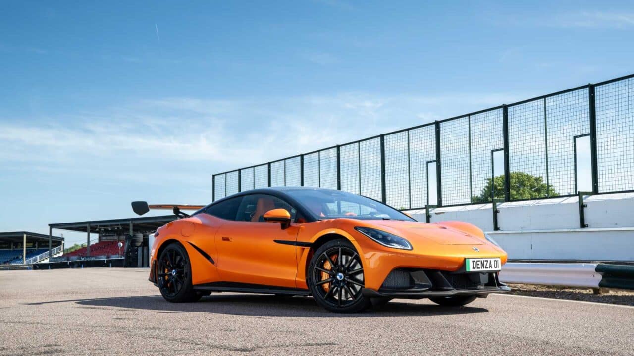 Denza Z Racing na cor laranja acelera em uma pista, exibindo aerofólio traseiro, linhas aerodinâmicas e visual esportivo