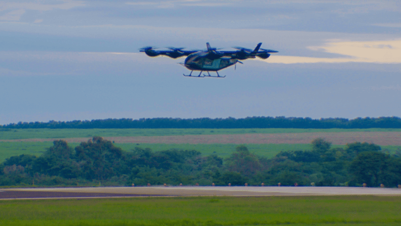 Aeronave elétrica de decolagem e pouso vertical da Eve Air Mobility voando sobre uma pista de aeroporto