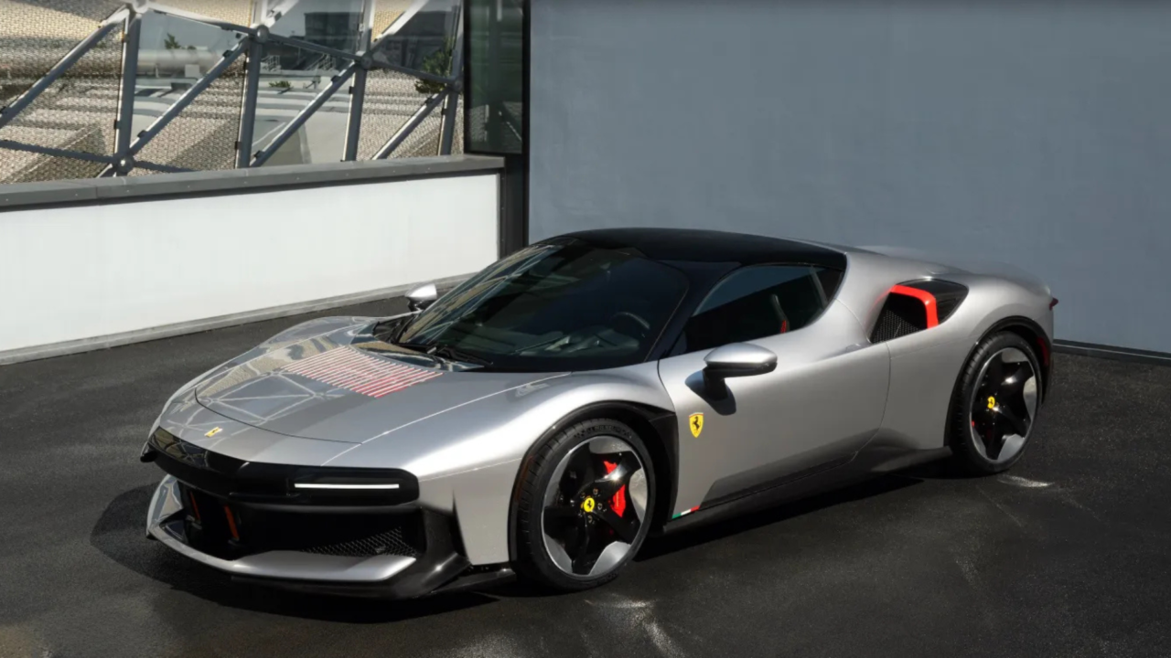 Vista lateral da Ferrari cinza metálica estacionada, com teto preto e detalhes aerodinâmicos