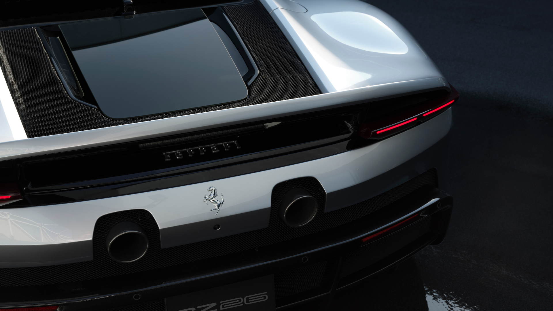 Detalhe traseiro da Ferrari cinza, mostrando o painel de fibra de carbono, escapamentos duplos e as lanternas finas em LED