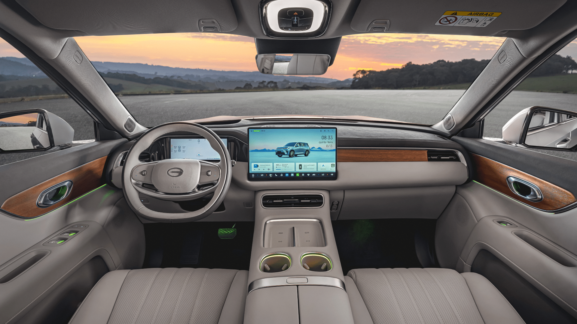 Interior do GS9 com acabamento em tom bege claro e madeira. O painel central possui uma grande tela multimídia com um aplicativo de navegação rodoviária. Destaque para o volante com logotipo da marca e as luzes ambiente em verde nas porta