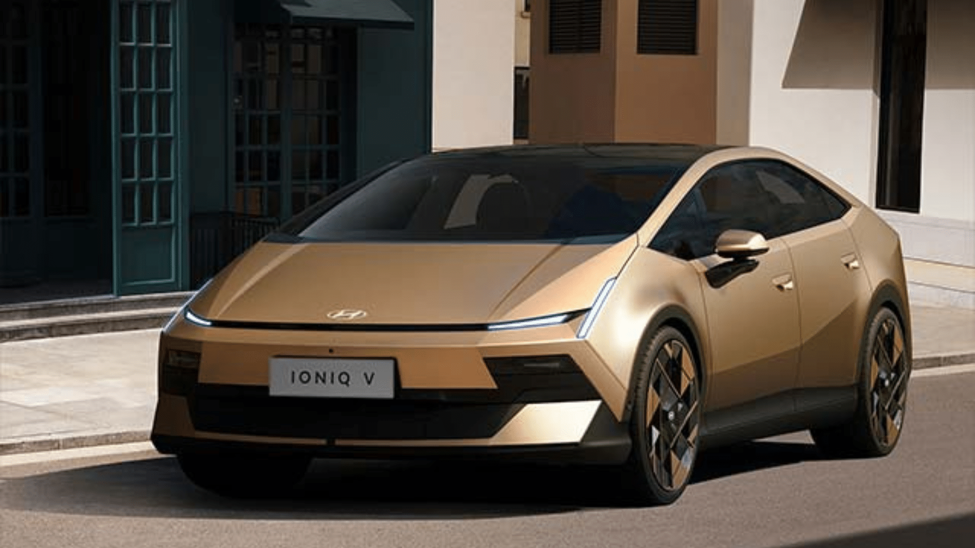 Hyundai Ioniq 5 na cor dourada/bronze estacionado em uma rua estreita entre prédios históricos. O carro possui um design angular, linhas retas e faróis em LED em formato de pixel