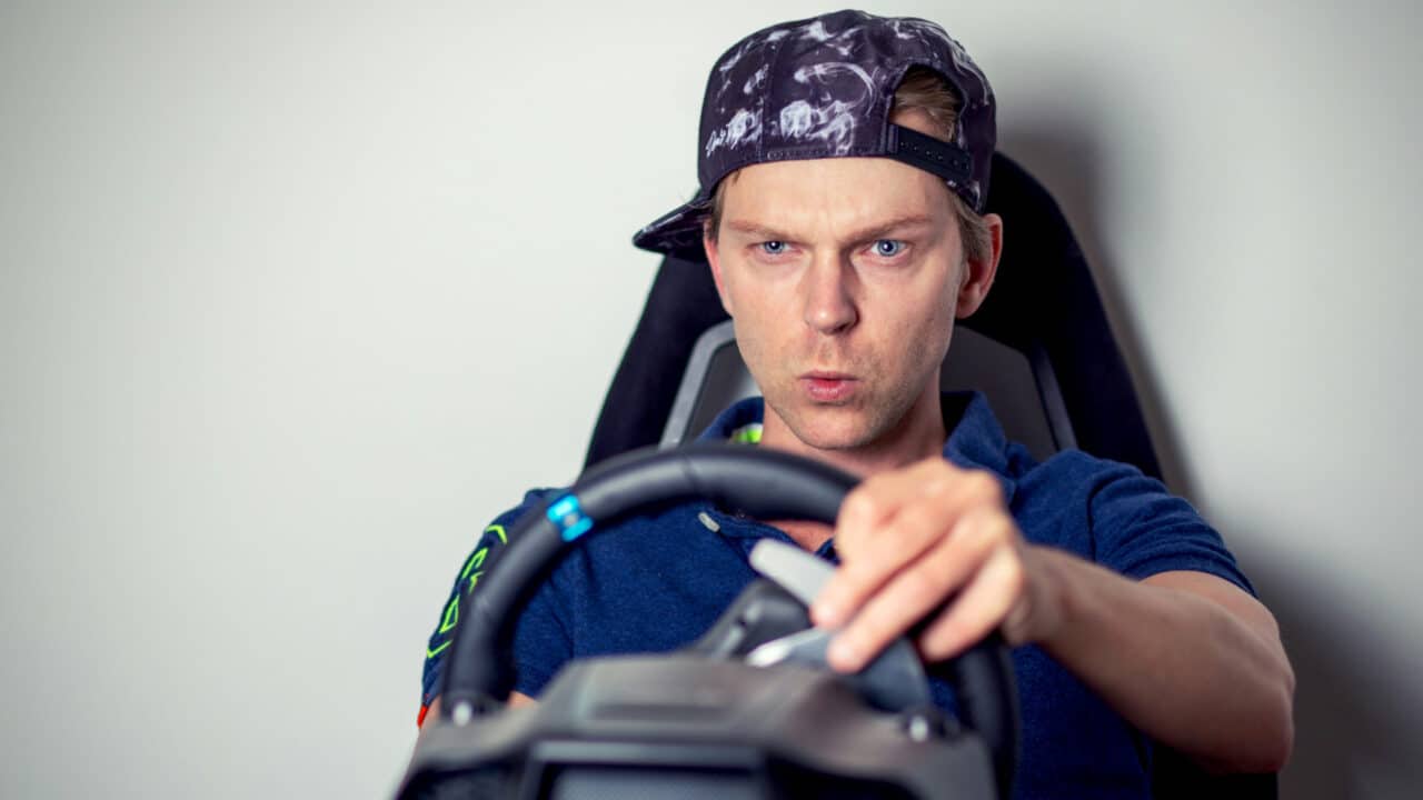 Foto de um homem com boné usando um volante de videogame