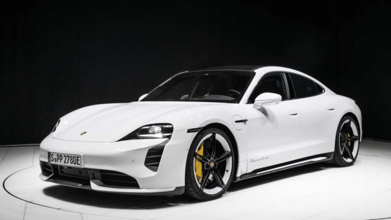 Porsche Taycan Turbo S branco em estúdio com fundo escuro, mostrando detalhes das rodas e a lateral do veículo