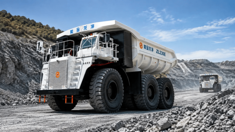 Caminhão de mineração gigante ZL230E com trabalhadores ao lado, em pátio industrial