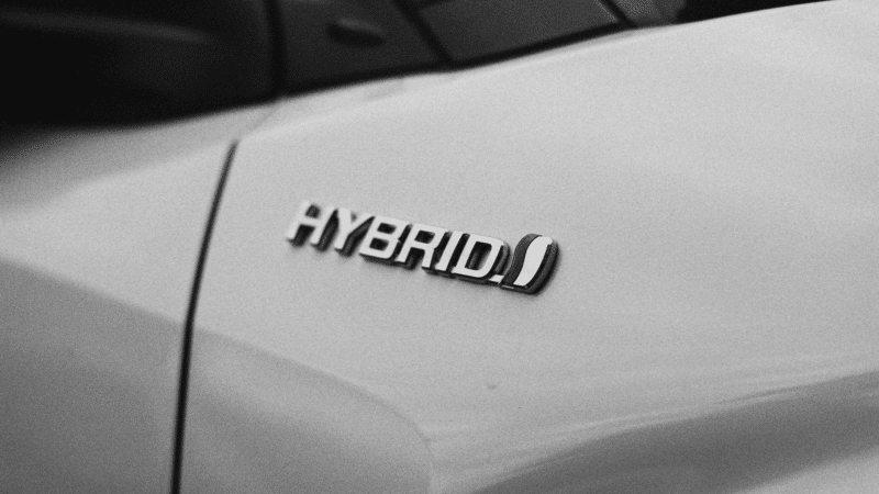 Detalhe em preto e branco do emblema 'HYBRID' na carroceria de um veículo