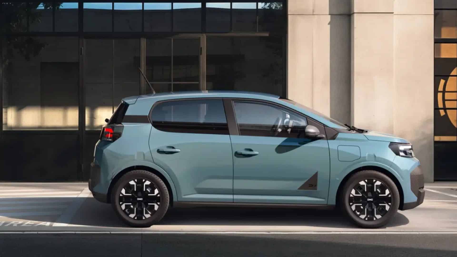 Vista lateral de perfil do Dacia Spring verde-água estacionado. É um hatchback compacto com linhas retas, maçanetas convencionais, rodas de liga leve pretas com detalhes prateados em formato geométrico e um discreto vinco na porta traseira