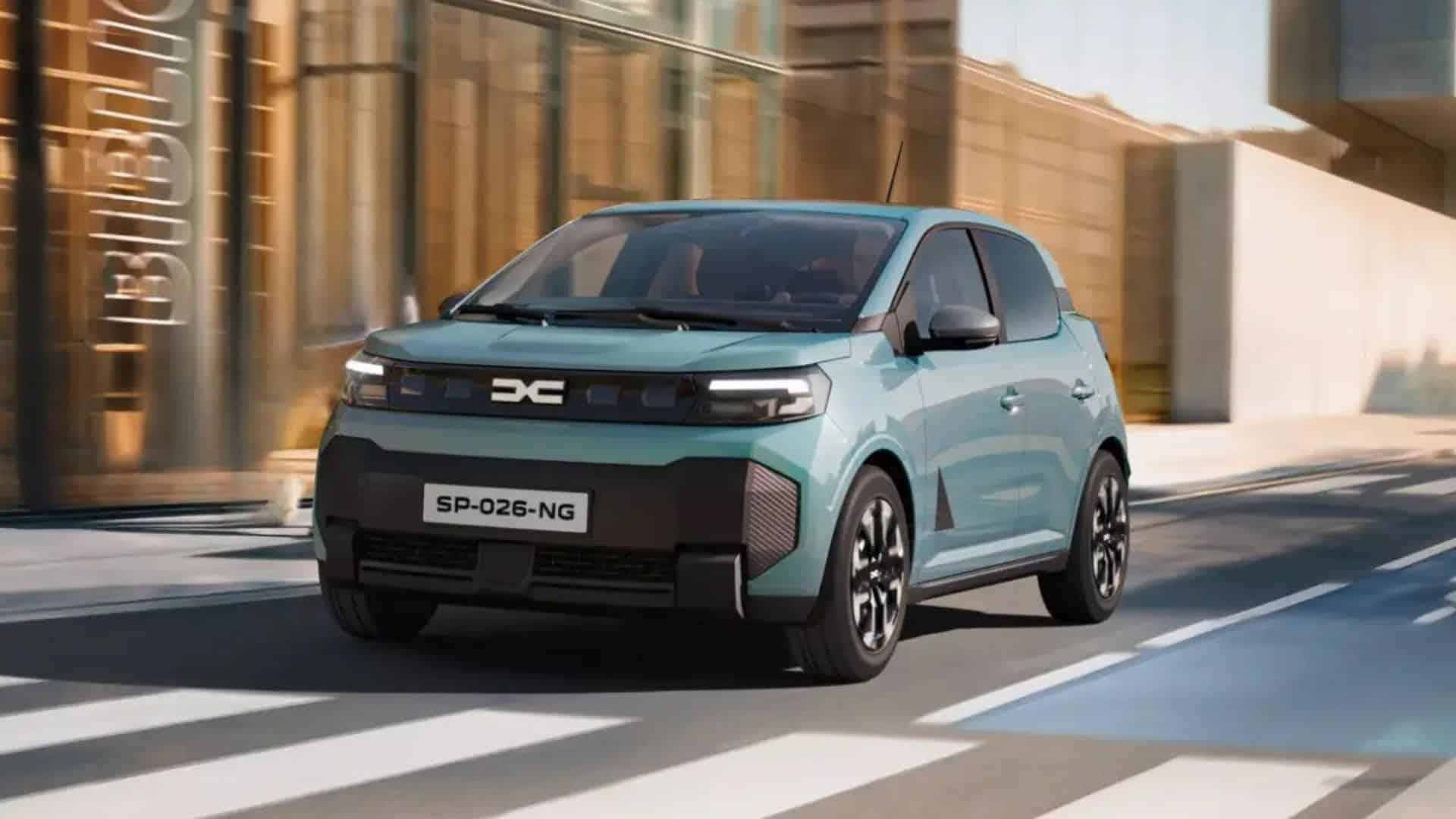 Dacia Spring verde-água em movimento pela cidade, capturado em ângulo frontal de três quartos. A imagem mostra levemente desfocada ao fundo para transmitir a sensação de velocidade. Destacam-se os vincos do capô, o farol dianteiro em LED e os detalhes em relevo no para-choque preto, além do contraste entre o carro e o asfalto com faixas de pedestres