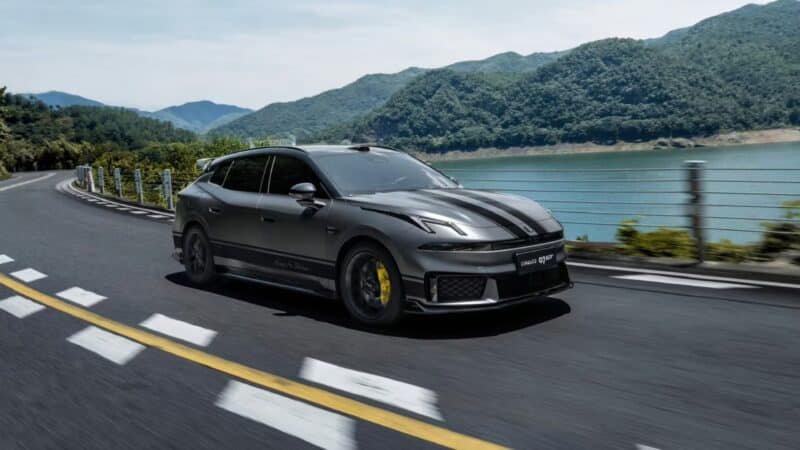 Veículo esportivo Lynk & Co 07 GT em alta velocidade em uma estrada panorâmica com vista para um lago e montanhas