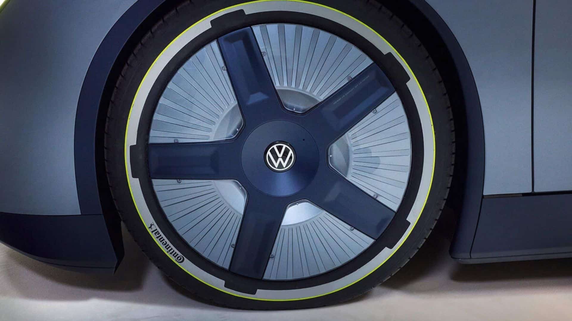 Close-up da roda dianteira do carro-conceito Volkswagen Mission Efficiency. A imagem destaca o design aerodinâmico da roda, com pneus Continental, detalhes em azul escuro, um aro fino amarelo brilhante e o logotipo da Volkswagen no centro