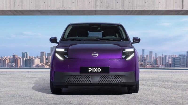 Vista frontal do Nissan PIXO na cor roxa, destacando os faróis de LED com formato angular e luzes diurnas verticais, o logotipo Nissan ao centro e a placa 'PIXO' na parte inferior