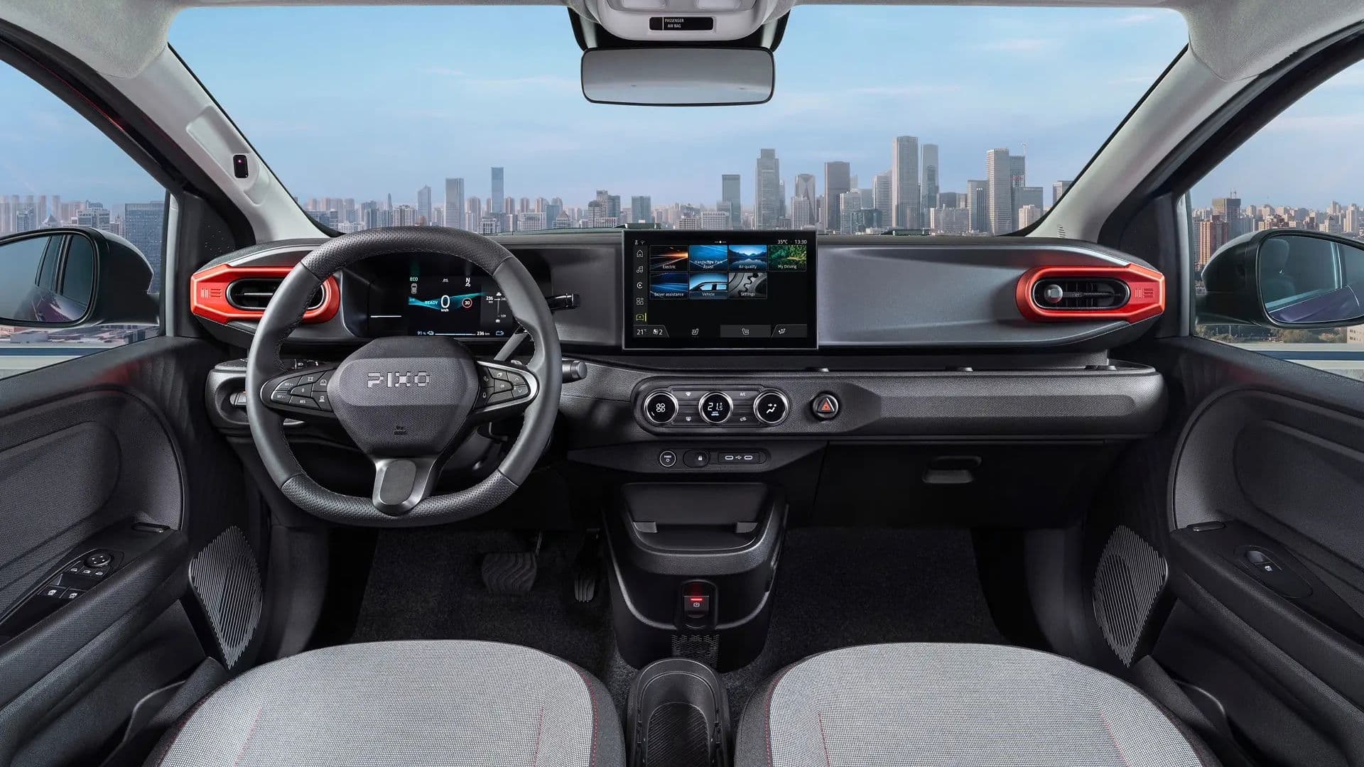 Vista interna do Nissan PIXO mostrando o painel de instrumentos digital, tela central de infoentretenimento, volante com o logotipo PIXO e detalhes em vermelho nas saídas de ar. Ao fundo, através do para-brisa, vê-se o horizonte de uma cidade