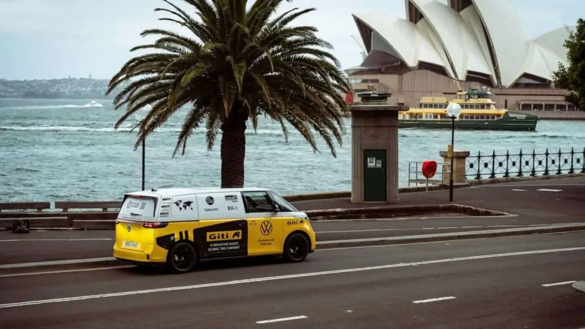 VW ID. Buzz na viagem recordista de Rainer Zietlow, em Sidney, Austrália.
VW ID. Buzz amarelo e branco estacionado em uma via à beira-mar em Sydney, com a Sydney Opera House e uma balsa verde e amarela ao fund