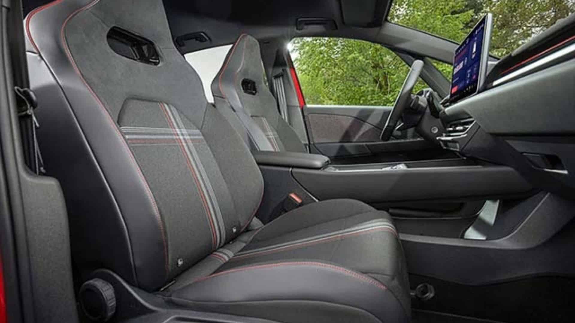 Interior do Volkswagen ID.3 GTI com bancos esportivos premium em padrão Superclark estilo tartan, costuras vermelhas, volante esportivo multifuncional com marcação vermelha e painel com faixa vermelha